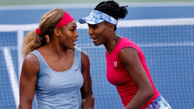 In this Aug. 28, 2014, file photo, Serena Williams, left, and Venus Williams talk between points against Timea Babos and Kristina Mladenovic during a doubles match at the 2014 U.S. Open.