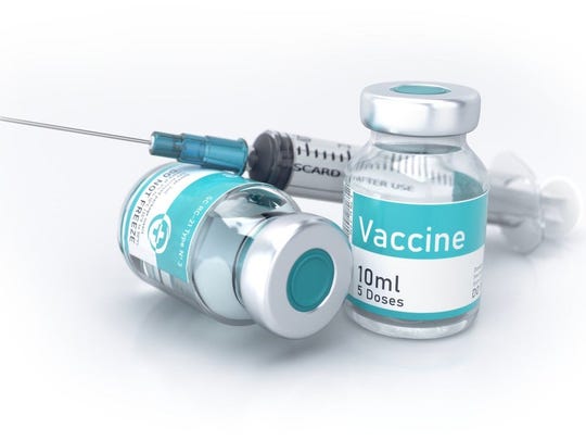 Two vials labeled vaccine next to a syringe.
