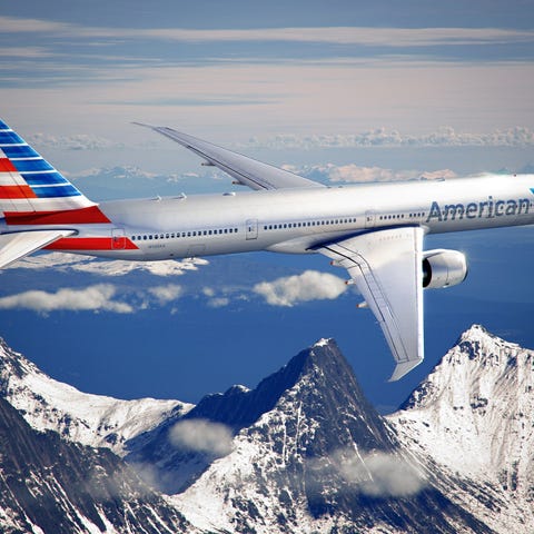 An American Airlines plane in flight, with mountai