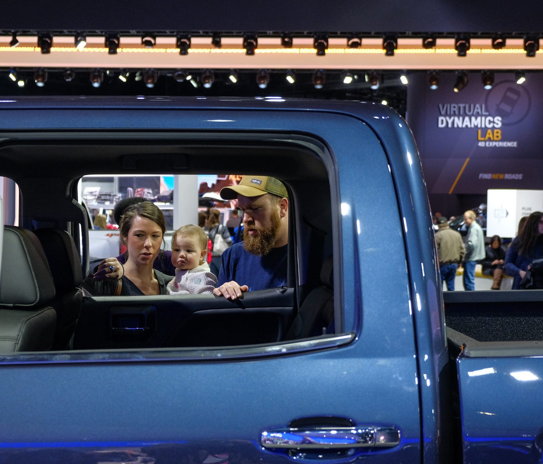 Marina Zolynsky, 30, of Royal Oak holds her daughter Montana, 1, while looking over trucks with her husband Jacob Zolynsky, 29, of Royal Oak at the Chevrolet display during the 2018 North American International Auto Show at Cobo Center in downtown De