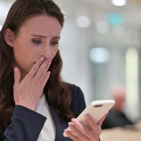 A concerned woman looks at her smartphone.