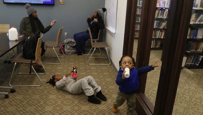 Sisters Markaysia Renford and Anastasia Renford of Rochester chat for a second while their niece and nephew entertain themselves.  Shiloh Drummond,5, played with her dolls while her brother, Sage, 1, wandered the private room at the Irondequoit Public Library with his bottle of milk.  The two sisters, along with another sister, not the mother of the children, had reserved the room to charge up their electronics, do homework and entertain the two children without disturbing others.  They werenÕt the only ones.  The other rooms along the floor had also been reserved by various people.