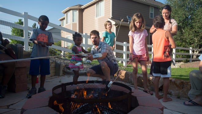 Jed Link huddles around a fire pit to roast marshmallows with neighbors and family friends in the backyard on Tuesday, July 11, 2018. 