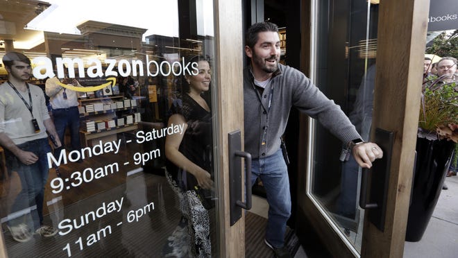 Employees greet the first customers at the opening day for Amazon Books, the first brick-and-mortar retail store for online retail giant Amazon.