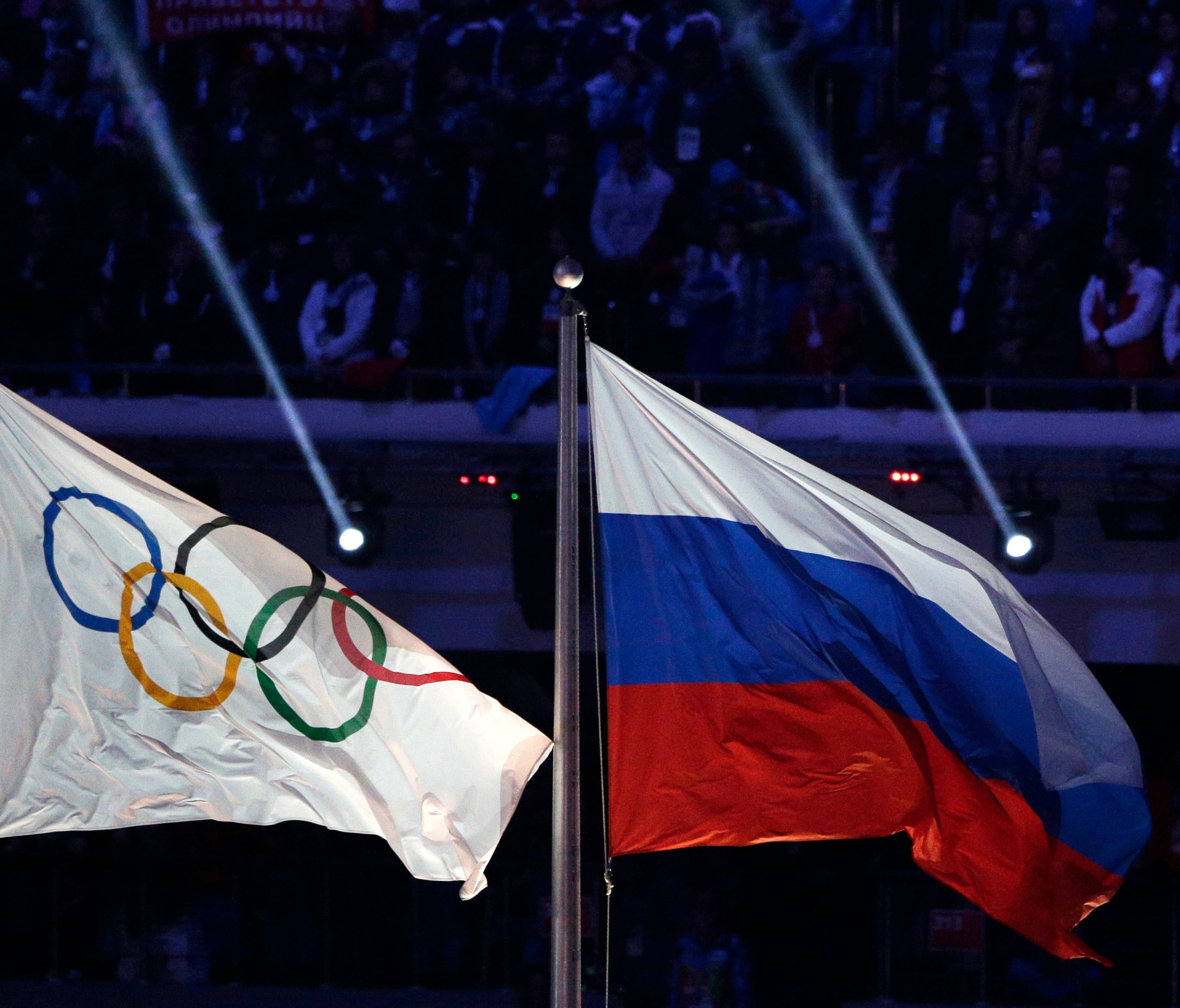 In this Feb. 23, 2014 file photo, the Russian national flag, right, flies after it is hoisted next to the Olympic flag during the closing ceremony of the 2014 Winter Olympics in Sochi, Russia.