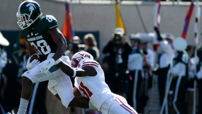 Michigan State wide receiver Monty Madaris picks up 16 yards on a reception before being tackled by Wisconsin safety Lubern Figaro during the third quarter of UW's game against Michigan State Saturday at Spartan Stadium in East Lansing, Mich.