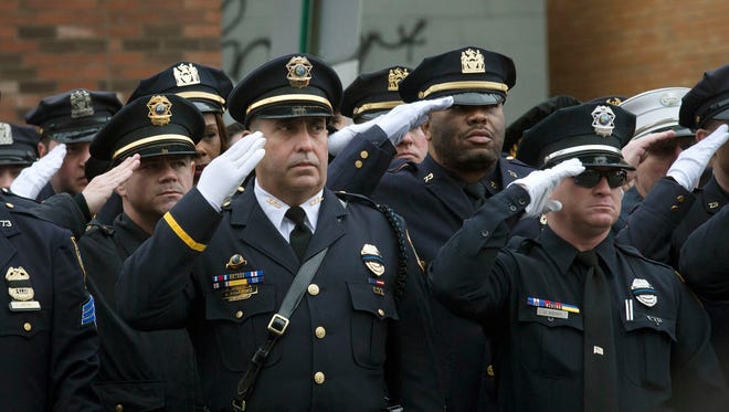 Police officers salute along the procession route during the funeral of New York Police Department Officer Wenjian Liu on Jan. 4, 2015, in Brooklyn. The ambush killing of Liu and his partner, officer Rafael Ramos, prompted Congress to pass the Blue Alert Act of 2015.
