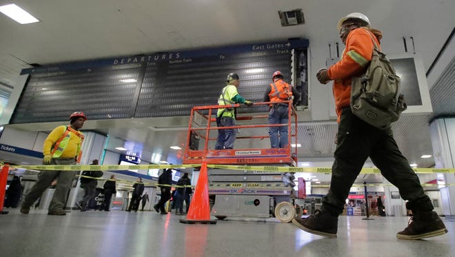 Workers replacing the train status board at Penn Station on Monday.