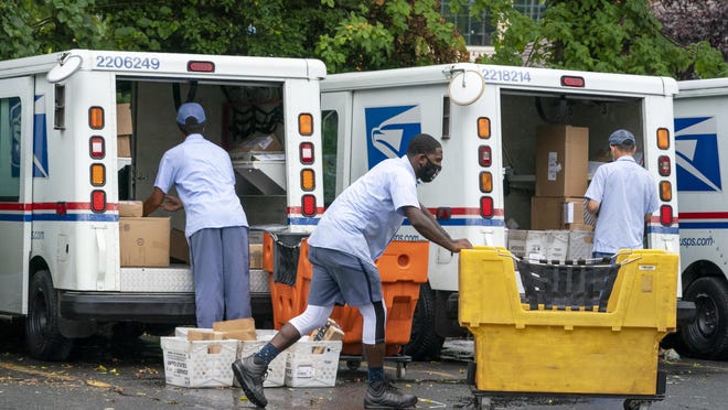 Letter carriers load mail trucks for deliveries at a U.S. Postal Service facility in McLean, Va., Friday, July 31, 2020. President Donal Trump has repeatedly raised unsubstantiated fears of fraud involving mail-in voting, which is expected to be more widely used in the November election out of concern for safety given the COVID-19 pandemic.