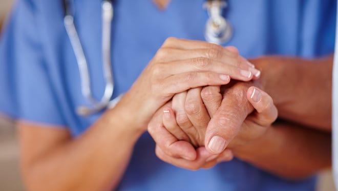A nurse holds a patient's hand.