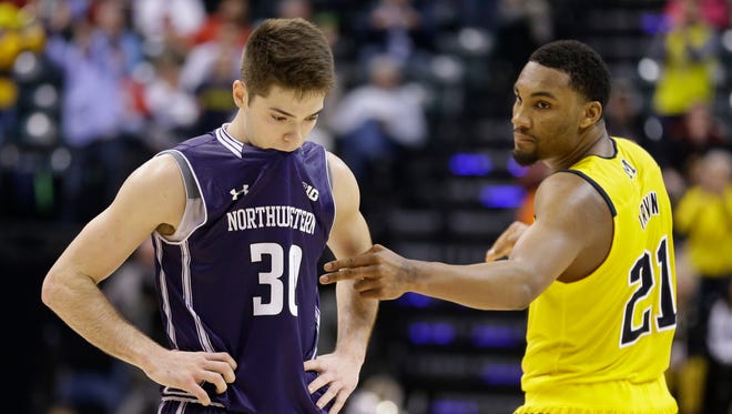 Northwestern's Bryant McIntosh looks down as Michigan's Zak Irvin, right, talks to him after a Big Ten tournament game Thursday, March 10, 2016, in Indianapolis.