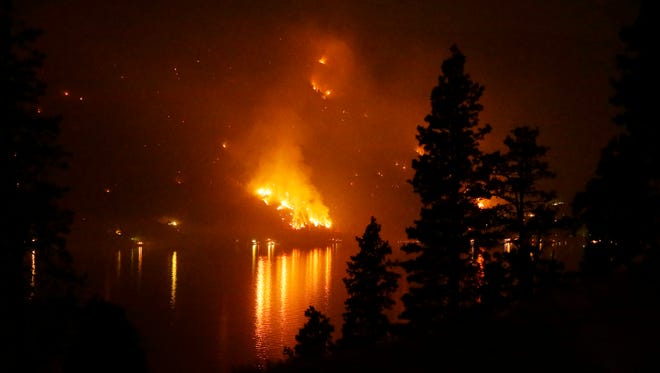 In this Aug. 17, 2015 file photo, timber burns in the First Creek fire near lakeside structures on the western shore of Lake Chelan near Chelan, Wash.