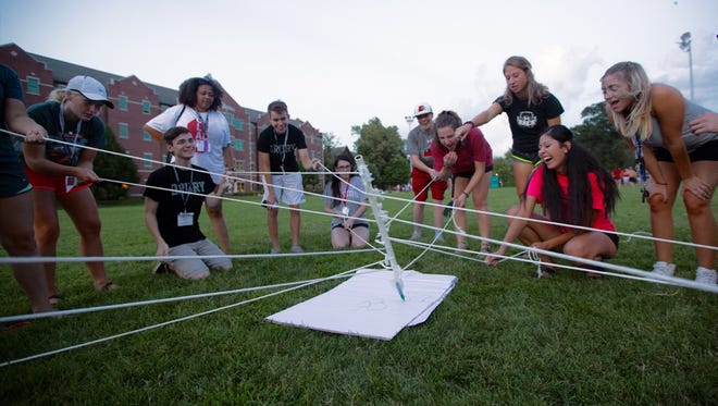Freshmen in one of Drury’s CORE classes work together in an attempt to draw an image on paper using strings attached to a marker during orientation weekend.