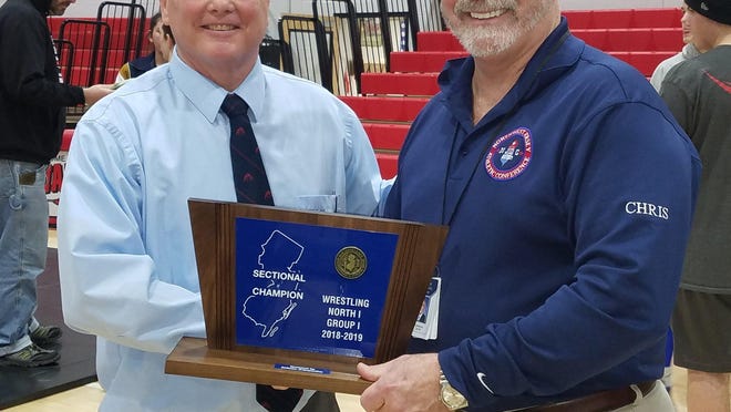 Kittatinny athletic director Chris Carroll, right, hands off the North 1, Group 1 sectional championship wrestling trophy to head coach John Gill after the Cougars defeated Emerson-Park Ridge in February 2019 in Emerson Boro.