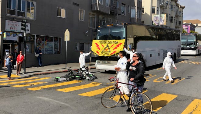 A group of activists block commuter tech buses in the Mission District with motorized scooters during a protest in San Francisco on Thursday.