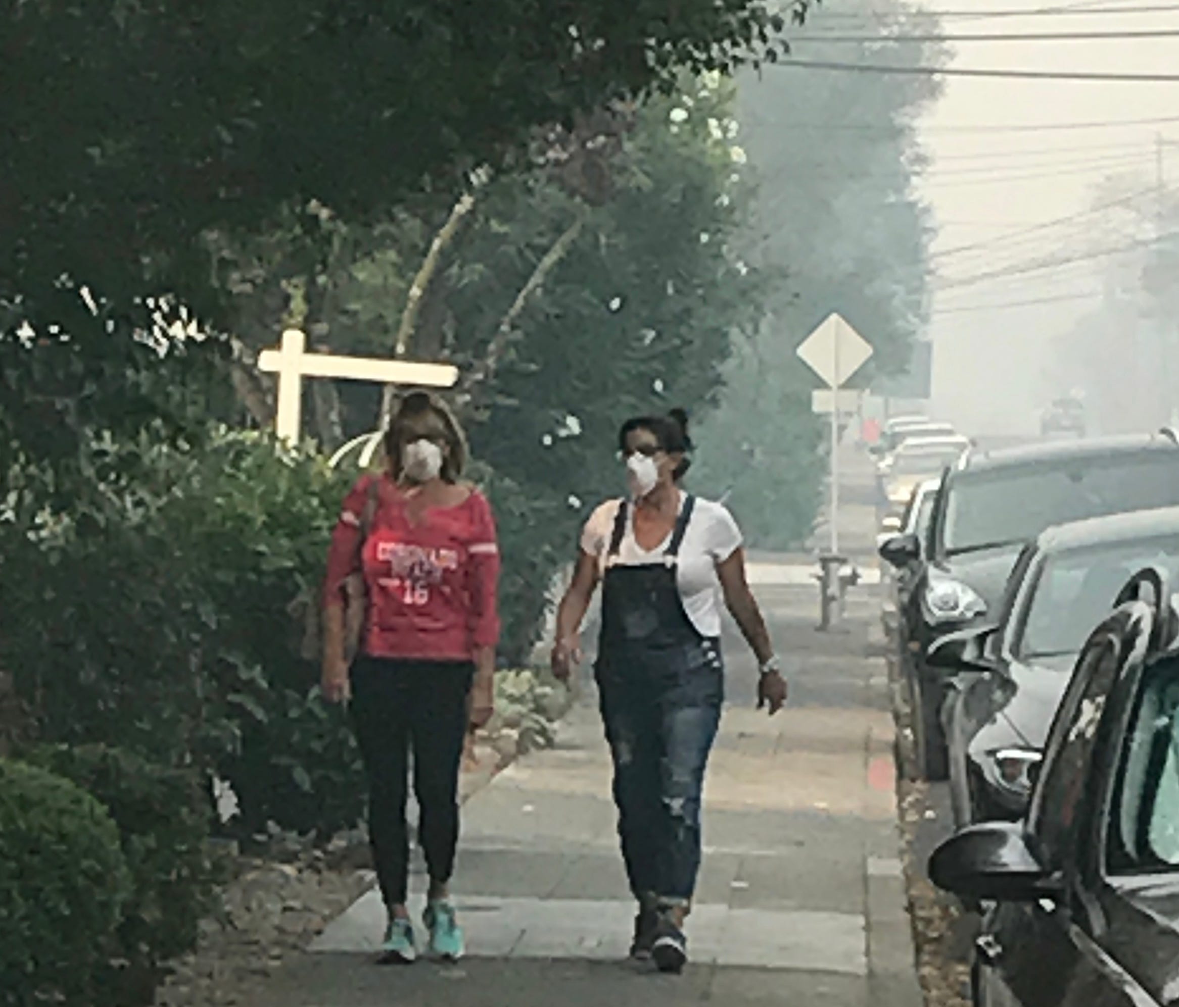 Women walking in Sonoma, Calif. wearing face masks to keep out the smoke and particulate matter in the air due to the wildfires in the area.