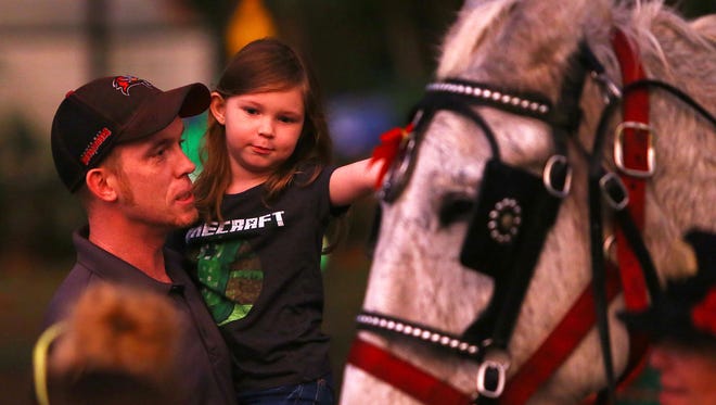 Riley Thompkins, 5, and her father Brendan take a closer look at Moonshine the Mule of Charlene's Classic Carriages during Holiday in the Park, Tuesday, Dec. 6, at Riverside Park.