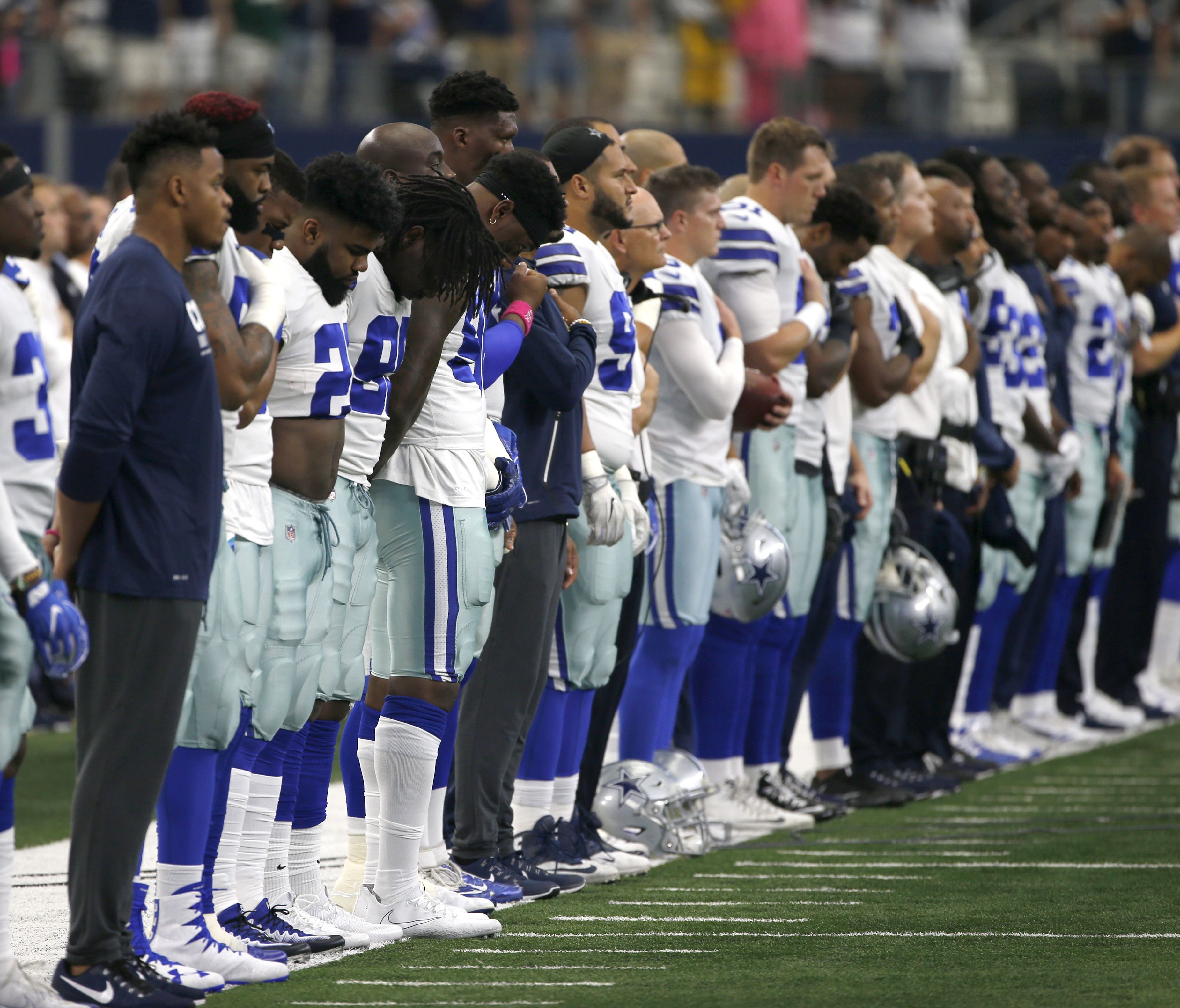 The Dallas Cowboys and staff stand on the sideline during the playing of the national anthem before the first half of an NFL football game against the Green Bay Packers on Sunday, Oct. 8, 2017, in Arlington, Texas.