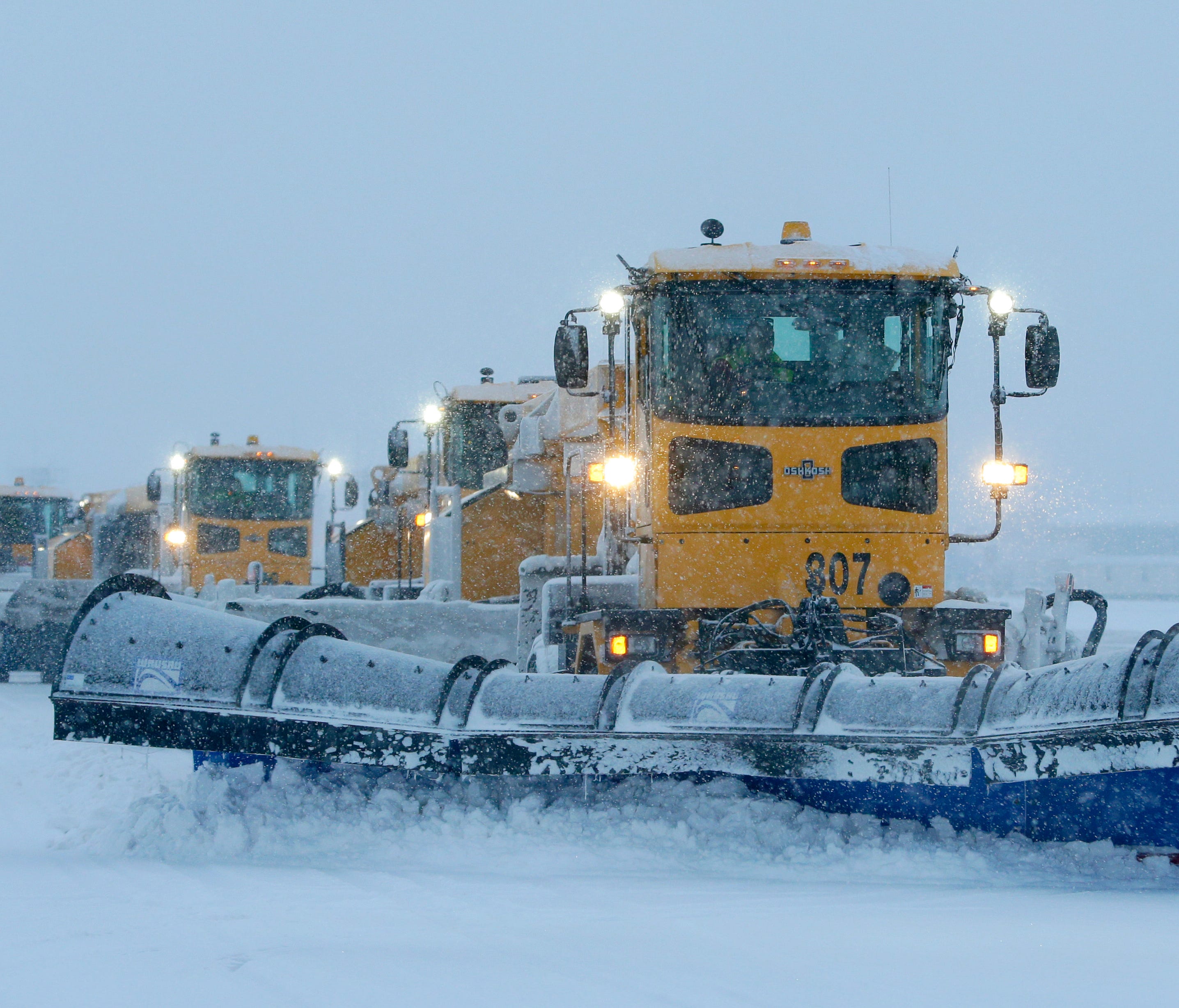 Plows are lined up as they begin snow removal on a runway Monday at Mitchell International Airport.