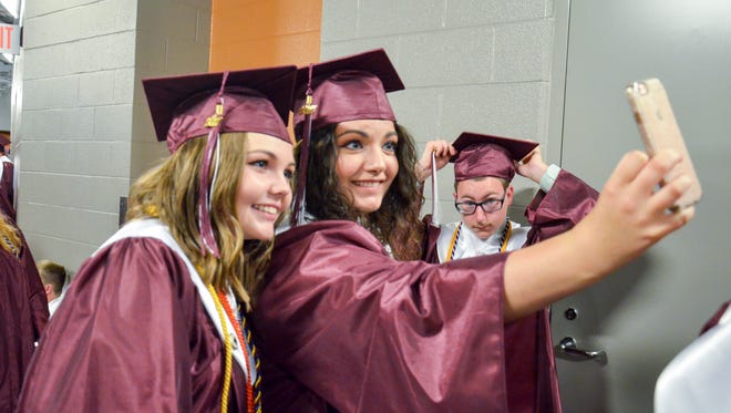Hannah Hudnall , right, and Emalee Hogan take a photo while waiting in line before the Henderson County High School Commencement Ceremony at the Ford Center Friday May 19, 2017