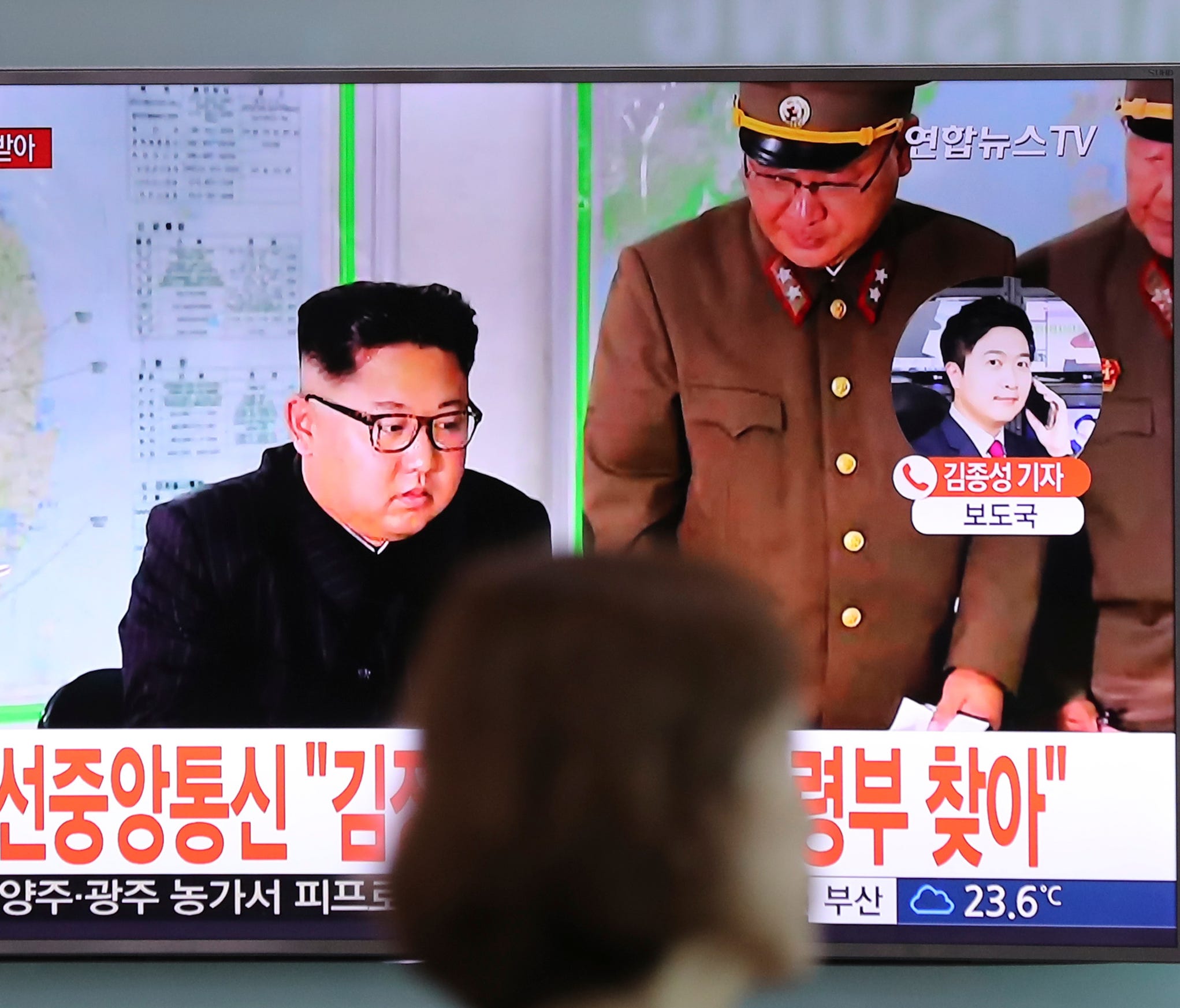 A woman walks by a TV screen showing a local news program reporting about North Korean military's plans to launch missiles into waters near Guam, with an image of North Korean leader Kim Jong Un, at Seoul Train Station in Seoul, South Korea, Tuesday,