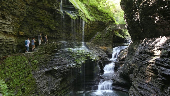 Visitors walk along the Gorge Trail and pass underneath the iconic Rainbow Falls at Watkins Glen State Park in Watkins Glen. The falls is one of two that visitors can walk underneath.