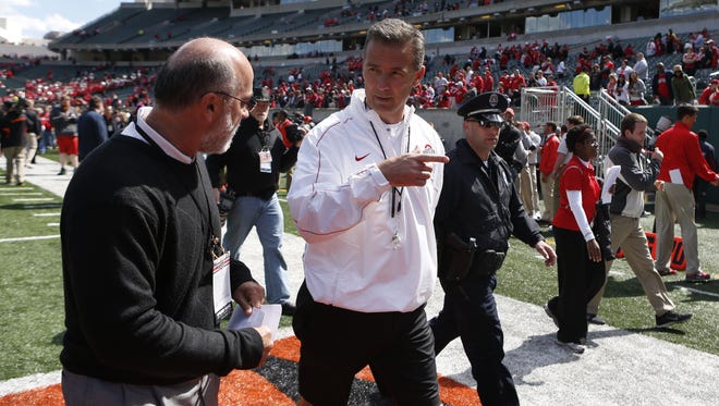 Urban Meyer walks off the field at Paul Brown Stadium after Ohio State held its spring game there in 2013. Meyer played football at UC and graduated with a degree in psychology in 1986 and his sister, GiGi is vice provost for undergraduate affairs there.