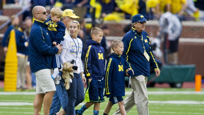 Former Michigan coach Lloyd Carr, far right, leads his grandsons T.J. and Tommy Carr, daughter-in-law Tammi Carr, and son Jason Carr, far left, holding son Chad Carr, onto the Michigan Stadium field for the pregame coin toss, Sept. 12, 2015. Chad Carr, 5, died from an inoperable brain tumor in November.