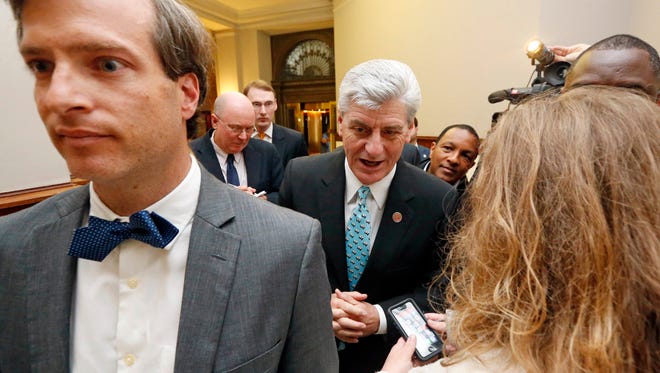 Republican Gov. Phil Bryant, center, walks behind his spokesman, Clay Chandler, left, as reporters ask him if he will sign a bill that would let government employees and private businesses cite religious beliefs to deny services to same-sex couples who want to marry, following a news conference on a youth jobs program at the Capitol in Jackson, Miss., Friday, April 1, 2016. Bryant would not say whether he will sign House Bill 1523, noting he had not received it yet and would need to study it first. Chandler tried to block reporters from asking questions by saying repeatedly: "Not today. Not today."