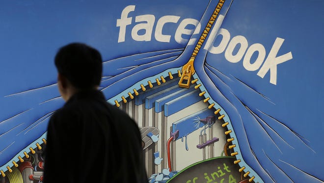A man passes a mural on the Facebook campus in Menlo Park, Calif.