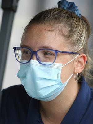 Erin Reynolds dons her mask as she parks and sanitizes golf carts Monday at the Sanctuary Golf Club in North Canton.