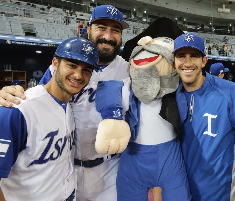 Israel players pose for photographs with the team mascot, 