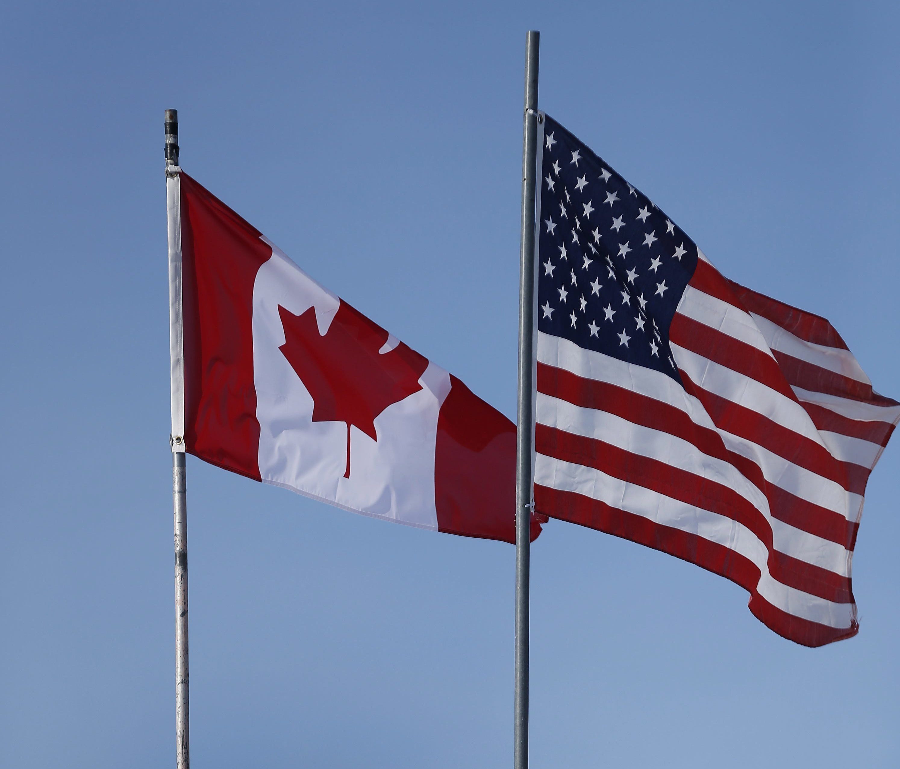 In this Feb. 9, 2017, file photo, an American flag and a Canadian flag fly above Maple Leaf Motel's office in Emerson, Manitoba.
