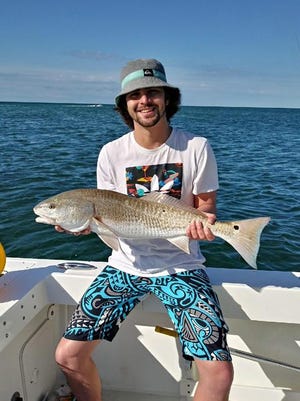 An anger from Massachusetts shows off a redfish he caught while fishing with Capt. Taylor Bankston on Destin Inshore Charters in 2021.