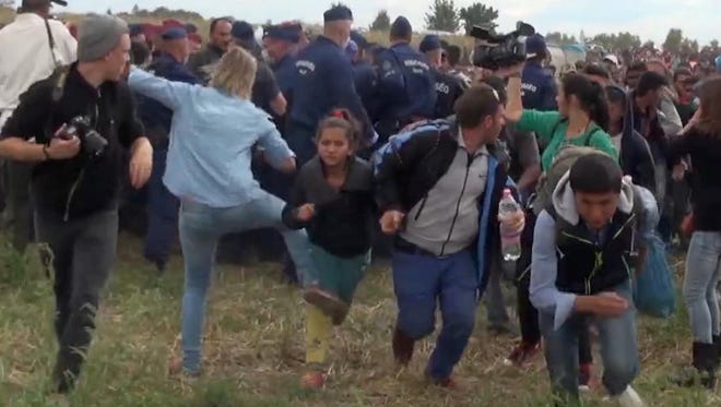 In this image taken from TV, a Hungarian camerawoman kicks out at a young migrant who had just crossed the border from Serbia near Roszke,  Hungary on Tuesday.