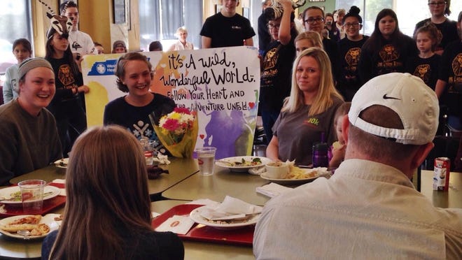 Kaylee Troxel (holding flowers) reacts with family Saturday at Jason’s Deli after learning her wish to travel to Malawi, Africa had been granted.