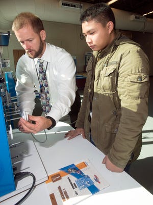 Escambia County School district Workforce education curriculum specialist, Steven Harrell, left, gives Pensacola High School student, Olygen Quizon, right, a demonstration on gear ratios and the manufacturing process.