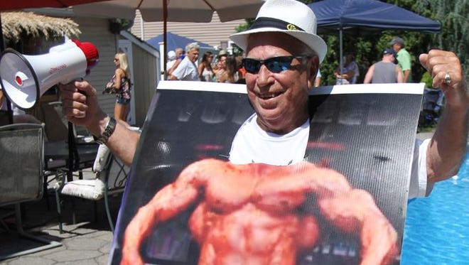 Mike Bellisano, who celebrated his 80th birthday in May, jokes around using a poster board of a muscleman during the Bellisano 50th family reunion in Howell, Sunday, August 10, 2014.