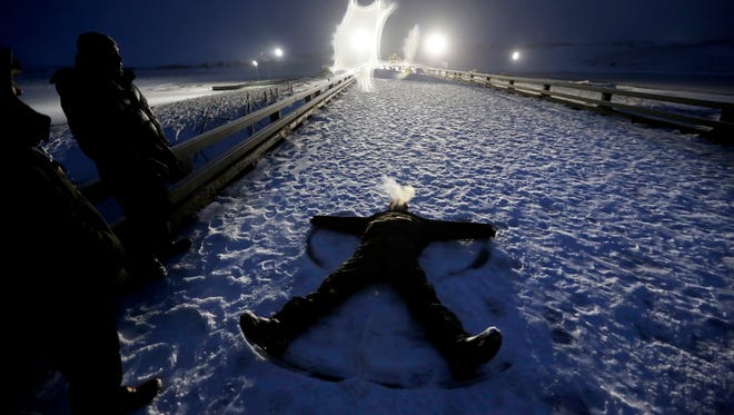 Army veteran James White, a member of the Lakota Native American tribe, makes a snow angel on a closed bridge during a protest across from police protecting the Dakota Access oil pipeline site in Cannon Ball, N.D., Dec. 1, 2016. 