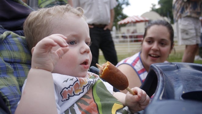 Gabriel McKinney, 15 months, enjoys a corn dog at the Montana State Fair in this file photo.