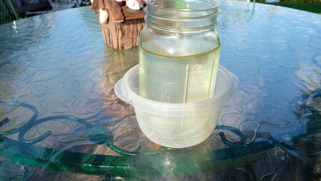 A water sample taken by Clinton Township resident Tom Tailford from the river in his backyard. The oil sheen had traveled down the Teske Drain approximately 1,000 feet north of 15 Mile Road.