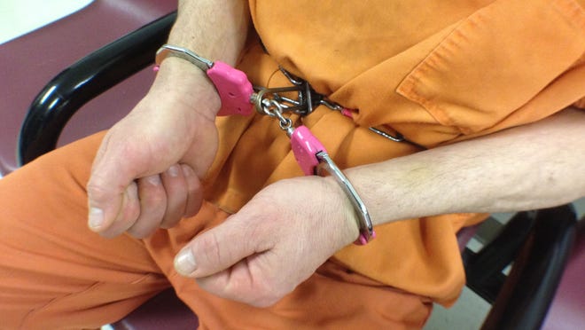 An inmate at the Tippecanoe County jail demonstrated on Monday, May 18, 2015, how handcuffs are attached to a metal waist chain that restricts a prisoner’s ability to move their hands up and down or to the side.