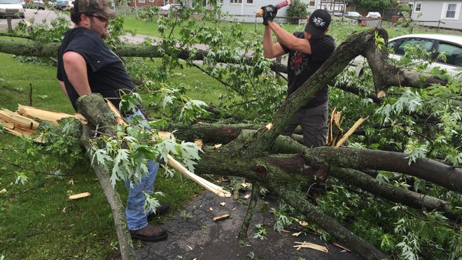 Irvington Street residents work to clear a fallen tree from a driveway Sunday morning.