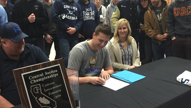 Central Valley Christian football player Blake Walker (center) signs his letter of intent to play college football with San Jose State.