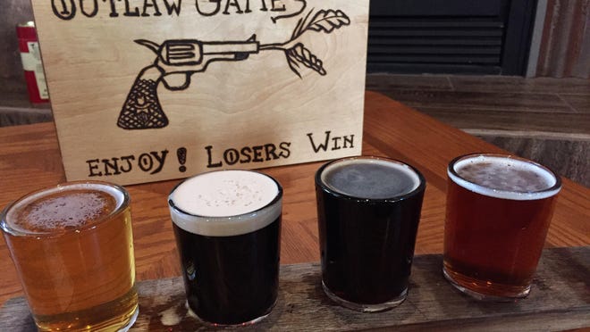 A flight of beer at Outlaw Brewing awaits drinking. The tap room has cozy chairs in a corner with a fireplace, as well as games to play.