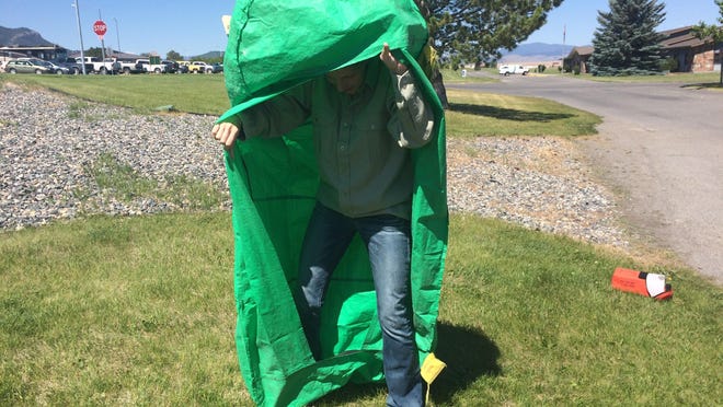 Kathy Bushnell demonstrates how to properly use a fire shelter with a green practice shelter. Real fire shelters are silver and resemble aluminum foil.
