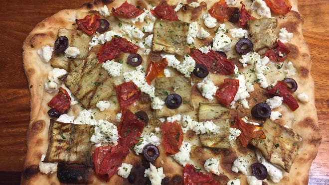 Grilled eggplant, goat cheese, and Kalamata olive pizza with fire-roasted tomatoes and Tuscan herb olive oil, prepared by Ray Sheehan of Neptune.