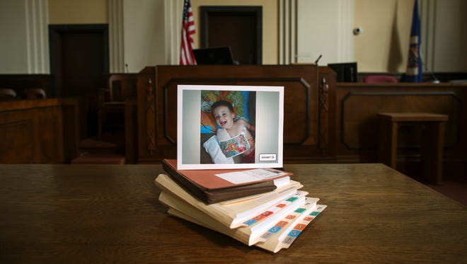 FILE - This July 15, 2014 file photo shows a photograph of Eric Dean, with a broken arm, placed on folders of exhibits and documents presented in court in Glenwood, Minn., relating to the May 2014 trial of Amanda Peltier in the death of her 4-year-old stepson, Eric. In 2014, the Minneapolis Star-Tribune ran an in-depth story reporting how Eric's plight drew little scrutiny despite 15 separate abuse reports being lodged with social workers. In response, Gov. Mark Dayton ordered closer oversight of child-protection decisions and formed a task force that recommended dozens of steps to place more emphasis on child safety.