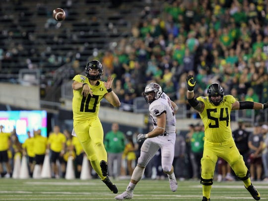 Sep 14, 2019; Eugene, OR, USA; Oregon quarterback Justin Herbert (10) throws a second quarter touchdown pass to wide receiver Johnny Johnson III (3) , not pictured, with pressure from Montana linebacker Dante Olson (33) and help from Oregon right tackle Calvin Throckmorton (54) against Montana at Autzen Stadium. Mandatory Credit: Rob Kerr-USA TODAY Sports