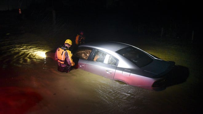 Rescue staff from the Municipal Emergency Management Agency investigate a flooded car during the passage of Hurricane Irma through the northeastern part of the island in Fajardo, Puerto Rico. 